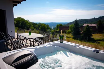 a hot tub on a patio with a table and a bottle of wine at Wellness bungalov - vodní nádrž Slapy - 40km od Prahy in Nečín