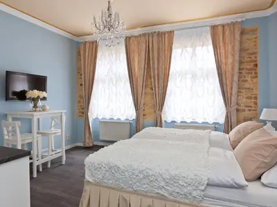 a bedroom with a white bed and a chandelier at Cathedral Prague Apartments in Prague