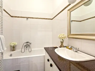 a bathroom with a sink and a tub and a mirror at Cathedral Prague Apartments in Prague