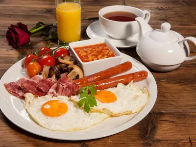a plate of breakfast food with eggs bacon beans and tomatoes at Cathedral Prague Apartments in Prague