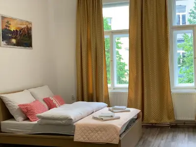 a small bedroom with a bed and two windows at KK Apartments in Prague