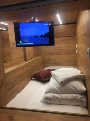 a room with a tv and a bed with pillows at Capsule Hostel Top Wenceslas square in Prague