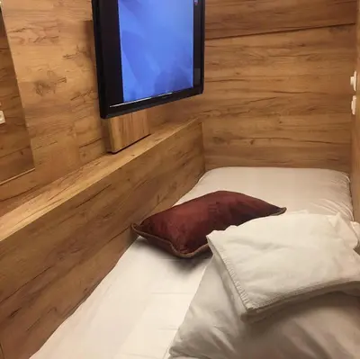 a room with a bed with a tv on the wall at Capsule Hostel Top Wenceslas square in Prague
