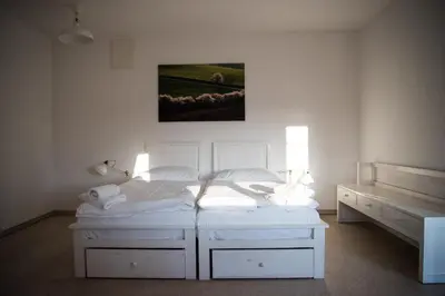 a bedroom with two white beds and a painting on the wall at Dvůr Perlová voda in Budyně nad Ohří