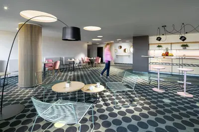 a woman walking in a room with tables and chairs at B&B Chuchle Arena Praha in Prague