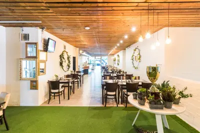 a dining room with tables and chairs and a green rug at B&B Chuchle Arena Praha in Prague