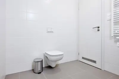 a white bathroom with a toilet and a trash can at Residence Port Karolina in Prague