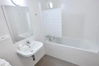 a white bathroom with a sink and a bath tub at Residence Port Karolina in Prague