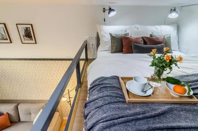 a bed with a tray with a vase of flowers and oranges at Royal Apartments Prague by Michal&Friends in Prague