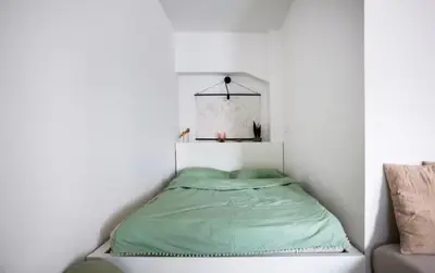 a bed in a white room with a green blanket at Modern Studio in Prague 7 in Prague