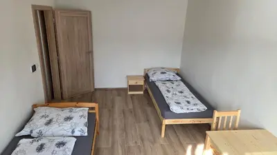 a room with two beds and a table and a door at Apartmán Mírová 472 B in Milovice