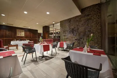 a restaurant with white tables and chairs and a brick wall at Hotel Kladno in Kladno
