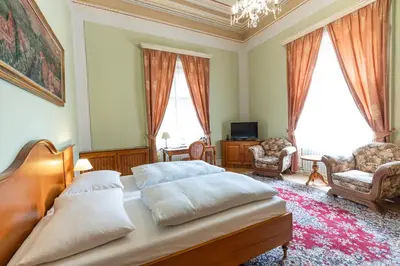 a bedroom with a bed and two chairs and a chandelier at Vila Lanna in Prague