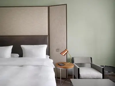 a bedroom with a bed and a chair and a lamp at The Emblem Prague Hotel in Prague