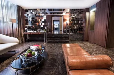 a living room with a couch and a table with a bowl of fruit at The Emblem Prague Hotel in Prague