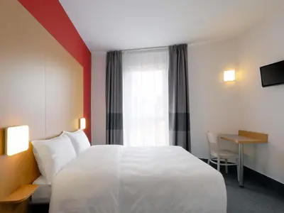a hotel room with a white bed and a desk at B&B Hotel Prague City in Prague
