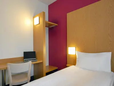 a bedroom with a bed and a desk with a laptop at B&B Hotel Prague City in Prague
