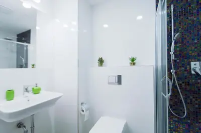 a white bathroom with a shower and a sink at Modern apartment Spanelska in Prague
