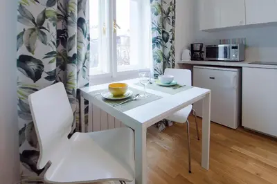 a kitchen with a white table and white chairs at Modern apartment Spanelska in Prague