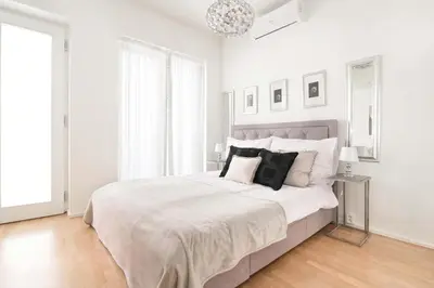a white bedroom with a large bed with black pillows at COZY&QUIET apartment with A/C in city centre in Prague