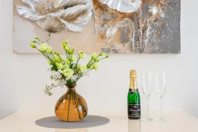 a bottle of champagne and a vase with flowers on a table at COZY&QUIET apartment with A/C in city centre in Prague