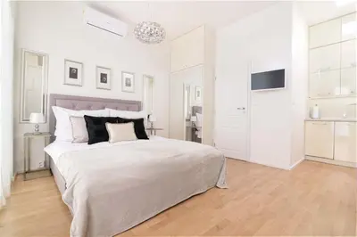 a white bedroom with a large bed and a television at COZY&QUIET apartment with A/C in city centre in Prague