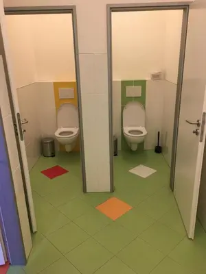 two toilets in a bathroom with green tiles at Expo capsule Hostel in Prague