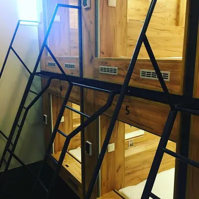 a ladder leading up to a room with wooden cabinets at Expo capsule Hostel in Prague