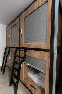 a bunk bed with a ladder and a window at Expo capsule Hostel in Prague
