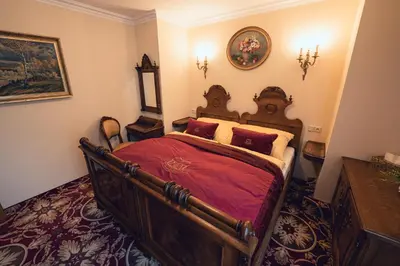 a bedroom with a large wooden bed with red sheets at Hotel Svatojánský Dvůr in Prague