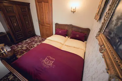 a small bedroom with a bed with red pillows at Hotel Svatojánský Dvůr in Prague