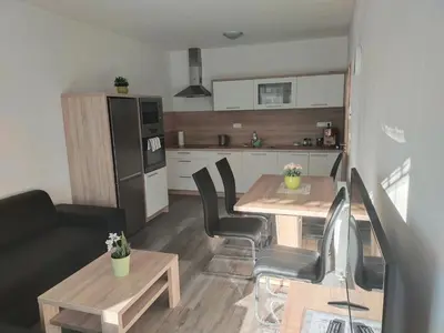 a living room with a table and a kitchen at Apartmán Karolína in Poděbrady