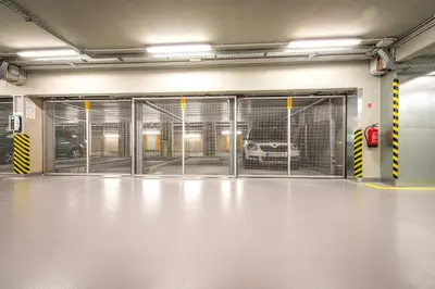 an empty parking garage with doors with a car in it at Quiet & new apartment near city center with garage in Prague