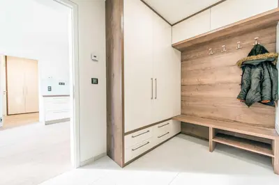 a dressing room with white cabinets and a wooden wall at Quiet & new apartment near city center with garage in Prague