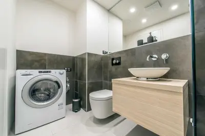 a bathroom with a washing machine and a sink at Quiet & new apartment near city center with garage in Prague