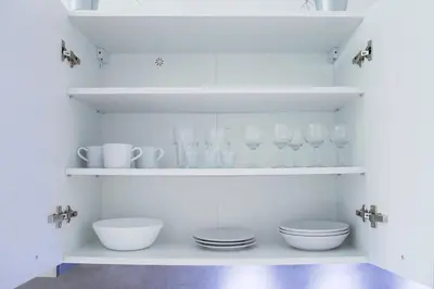 a kitchen with white shelves with dishes and glasses at Modern apartment Pricna 4 in Prague