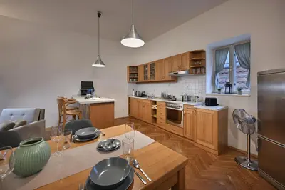 a kitchen with wooden cabinets and a table with a dining room at White Swan Boutique Apartments in Prague
