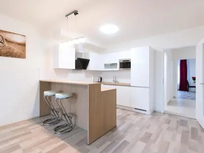 a kitchen with white cabinets and a bar with stools at Spacious 2BR with balcony in Prague - Comfort & Style in Prague