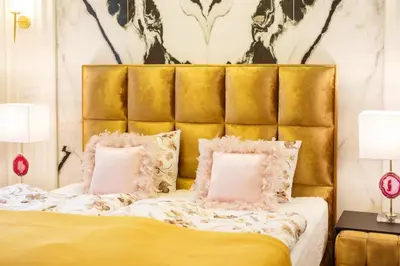 a bed with a gold headboard and two pink pillows at Palace Apartment by Main Station - President in Prague