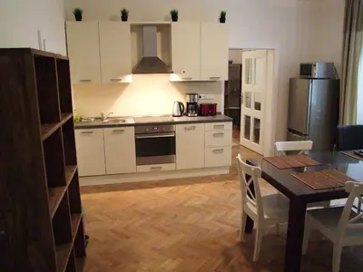 a kitchen with white cabinets and a table with a dining room at Selinor Old Town Apartments in Prague