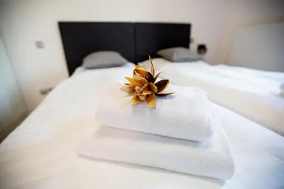 a pile of towels with a flower on a bed at Exclusive penzion Viva Residence in Mladá Boleslav