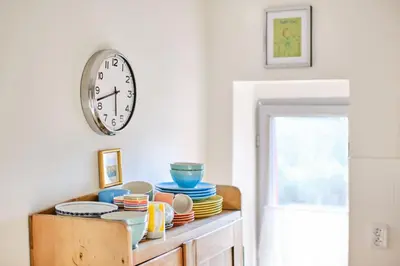 a clock on a wall above a table with dishes at Rusty's Cottage in Sedlčany