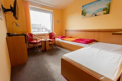 a bedroom with two beds and a table and chairs at Penzion Školička in Prague