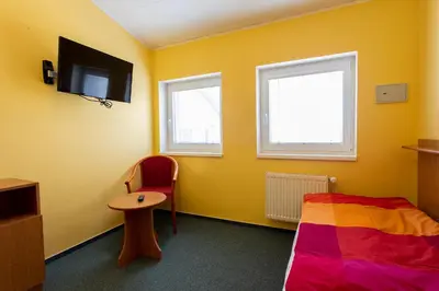 a room with a bed and a tv and a chair at Penzion Školička in Prague