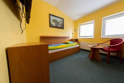 a bedroom with a bed and a chair and a table at Penzion Školička in Prague