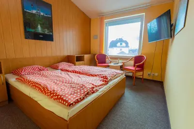 a bedroom with a bed and a table and a window at Penzion Školička in Prague