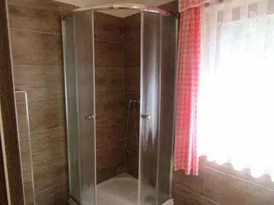 a shower with a glass door next to a window at Rekreační dům v Brdech Pod Svatou Annou in Ohrazenice