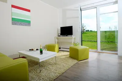 a living room with green chairs and a table and a tv at Black Bridge Hotel Apartment in Prague