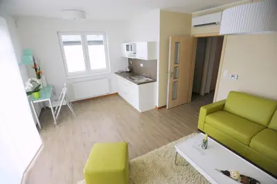 a living room with a green couch and a kitchen at Black Bridge Hotel Apartment in Prague