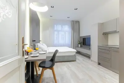 a bedroom with a bed and a table and a kitchen at Lampi Aparthotel Prague in Prague